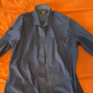 Mörkblå skjorta från Eton - Stilren mörkblå skjorta från Eton med klassisk krage och knäppning framtill. Skjortan har lång ärm och är tillverkad i ett slätt bomullstyg. Perfekt för dig som gillar en clean och tidlös look.