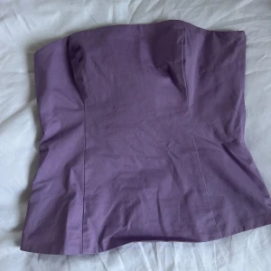 Ljuslila tubtopp från Samsøe Samsøe - Trendig ljuslila tubtopp från Samsøe Samsøe. Toppen är axelbandslös och har en enkel, stilren design med lätt figurnära passform. Perfekt att matcha med jeans eller kjol för en snygg look.