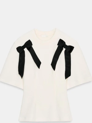 Vit topp med svarta rosetter - Supersöt vit topp med korta ärmar och två stora svarta rosetter på axlarna. 💖🎀Helt slutsåld på Zara!! Det är storlek S och i nyskick!