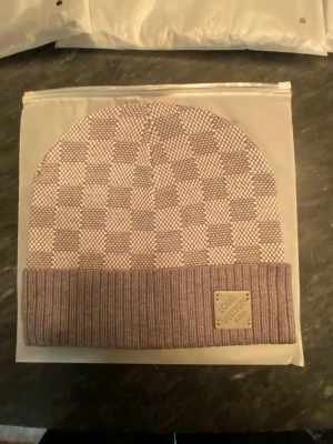 Grå Louis Vuitton mössa - Säljer en Grå mössa från Louis Vuitton i klassisk modell. Mössan kommer i originalförpackning med LV-logga på påsen. Perfekt accessoar för dig som vill ha en exklusiv touch på din outfit.