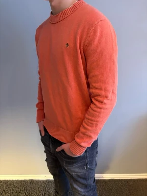 Morris tröja - Snygg korallfärgad stickad tröja från Morris med rund halsringning och ribbade muddar. Tröjan har en liten broderad logotyp på bröstet och är tillverkad i mjukt material. Storlek L men passar precis som M. Modellen är 184cm
