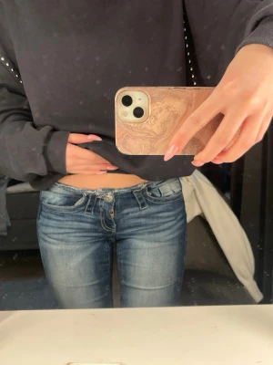 Blå x-tra low cut bootcut jeans - Säljer ett par blå jeans med extra låg midja och bootcut-ben. Jeansen har slitna detaljer, råa kanter upptill och nertill samt stora bakfickor med coola sömmar. Använda endast två gånger och kommer inte till användning då de är för små, strl xs från gina 14+