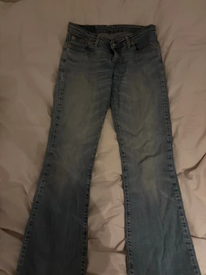 Levi's 517 ljusblå bootcut jeans - Ljusblå Levi's 517 jeans med klassisk bootcut passform och femficksmodell. Jeansen har en snygg tvättad look, normal midja och är tillverkade i slitstarkt bomullsjeans. Perfekta för dig som gillar retrovibbar och tidlös stil. midjemått rakt över: ung 38 cm innerbenslängd: ung 75 cm