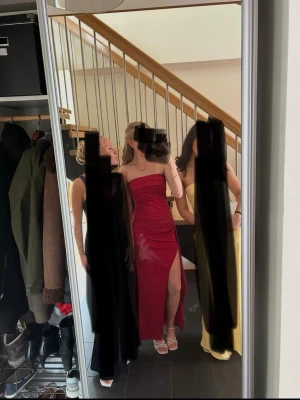 Röd axelbandslös klänning med slits - Säljer en röd, axelbandslös klänning med figurnära passform och hög slits på ena sidan. Klänningen är perfekt för bal eller festliga tillfällen. Klänning är endast använd 1 gång.