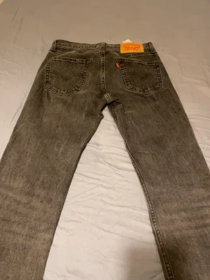 Levi's 501 grå jeans straight fit - Klassiska grå Levi's 501 jeans med rak passform och femficksdesign. Jeansen har en ikonisk knappgylf och är tillverkade i slitstarkt bomullsjeans. Perfekta för en avslappnad och tidlös stil. Pris kan diskuteras 