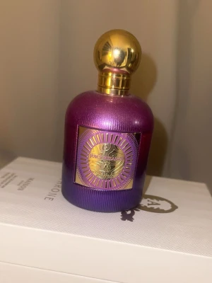 Juicy Couture parfym lila/guld - Juicy Couture parfym i en snygg lila flaska med guldig rund kork och dekorativ etikett. Doften har fruktiga, söta och pudriga toner med inslag av vanilj, trä, grönt och blommigt. Perfekt för dig som gillar färgstarka och lyxiga parfymer. (Ca 80% kvar) 