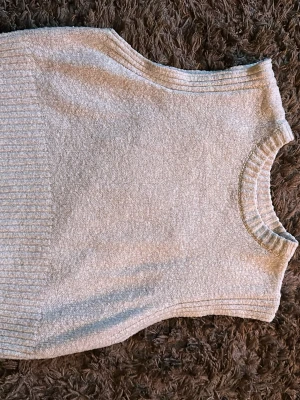  Beige stickad väst  - Säljer en ljusgrå stickad väst med ribbade detaljer vid halsringning och nederkant. Västen har en rak och boxig passform och är gjord i ett mjukt, strukturerat material som känns riktigt skönt. Perfekt att styla över en skjorta eller t-shirt❤️ frakt 30 kr❤️