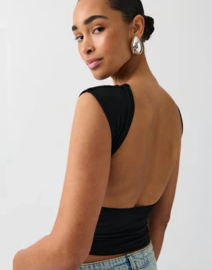 Svart topp från Gina - Säljer en populär svart topp med öppen rygg från Gina Tricot i storlek S. Toppen har en snygg draperad halsringning och är ärmlös, vilket ger en cool och modern look. Skriv gärna för fler bilder eller frågor💗