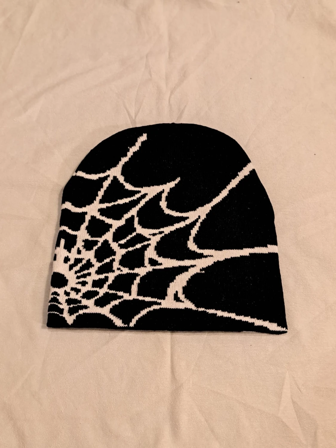 Svart stickad mössa med spindelnätsmönster