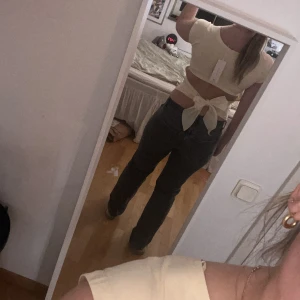 Ljusgul  topp med öppen rygg och rosett - Säljer en ljusgul  topp  i mjuk bomull. Toppen har korta ärmar, öppen rygg med stor knytrosett bak. Perfekt för dig som gillar trendiga detaljer och vill ha en söt look. Helt ny med prislapp 