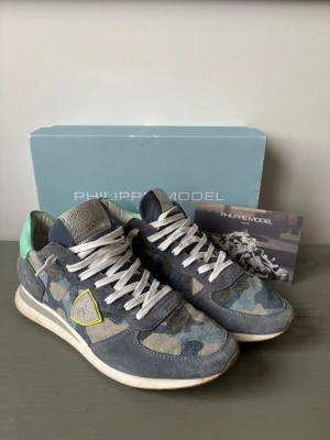 Nya Philippe Model blå camo sneakers! - Snygga sneakers från Philippe Model med camo färg de är nya men dock utan prislapp. Tillbehör för du kartong och kort men kartongen har märken från tejp. Skick 10/10. Pris 1799kr nypris ca 3300kr då passa på då de är nya