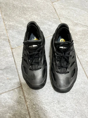 Svarta Adidas Climacool sneakers - Säljer ett par svarta Adidas Climacool sneakers med ventilerande mesh och syntetdetaljer. Skorna har snörning och en sportig, futuristisk design med rund tå och platt sula. Perfekt för dig som gillar stilrena och funktionella sneakers.