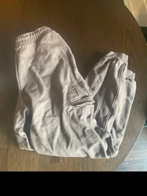 Bruna mjukisbyxor från Gymshark XS - Säljer ett par bruna mjukisbyxor från Gymshark i storlek XS. Byxorna har elastisk midja och ribbade muddar vid bensluten. Materialet är mjukt och skönt, perfekt för chill eller träning. Gymshark-logga broderad på benet.