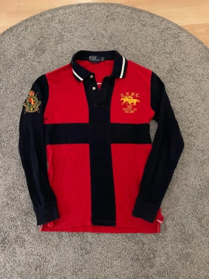 Polo Ralph Lauren skjorta - Säljer en röd och marinblå långärmad skjorta från Polo Ralph Lauren, Skjortan har broderade detaljer. Tröjan är markerad XL men passar M.