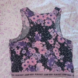 Blommig och leopardmönstrad linnetopp - En fin linnetopp från Lindex med lila och rosa blommor över svart leopardmönster. Ärmlös och i mjukt, stretchigt material. Den första bilden är bild på hur baksidan ser ut, skriv om ni vill att jag skickar bild på framsidan!💗