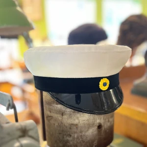 Klassisk studentmössa 52-63 - Klassisk studentmössa med vit ovandel i bomull, svart band och blank svart skärm. Framtill sitter en klassisk kokard. Insidan har det klassiska foder i blått och gult. Finns storlekar från 52 – 63. Limiterat lager