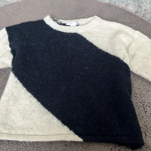 Svart och beige stickad tröja Gina Tricot - Säljer en stickad tröja från Gina Tricot i storlek 146/152. Tröjan har ett coolt diagonalt mönster i svart och beige, rund halsringning och långa ärmar. Perfekt  för dig som gillar en stilren men ändå unik look. ser väldigt konstig ut på bilden 