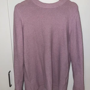 Ljuslila stickad tröja från Amisu - Supermysig ljuslila stickad tröja från Amisu med rund halsringning och ribbade muddar. Perfekt för lager-på-lager och chill dagar. Enkel och stilren design som är lätt att matcha med jeans eller kjol.