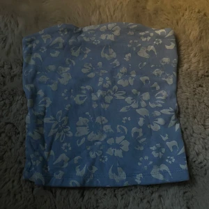 Hibiskus bandeau topp - Säljer en ljusblå bandeau tubtopp med vitt hibiskus mönster