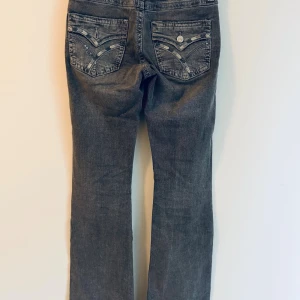 Grå jeans med broderade bakfickoru Gina Tricot - Snygga grå jeans från Gina Tricot i storlek 164. En knapp borta på en av bakfickorna. Bootcut, normal midja. 