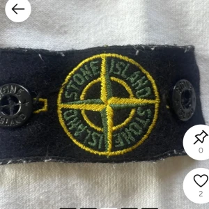 Vit hoodie från Stone Island Junior - Vit hoodie från Stone Island Junior med dragkedja framtill och klassisk logga på ärmen. Tröjan har huva, långa ärmar och två fickor med svarta detaljer. Perfekt för dig som gillar streetwear och vill ha något stilrent men ändå sportigt. Passar runt 170 - 180