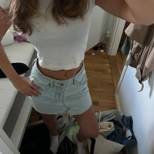 Ljusblå jeanskjol me - Säljer en ljusblå jeanskjol med klassisk femficksdesign. Kjolen har en kort passform och stängs med knapp och dragkedja framtill. Perfekt för dig som gillar en avslappnad och trendig stil.