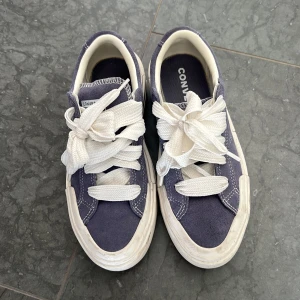 Converse sneakers i lila mocka - Säljer ett par Converse sneakers i lila mocka med chunky vit platt sula och breda vita snören. Skorna har rund tå och coola kontrastsömmar. Perfekta till jeans och ger en avslappnad vibe.