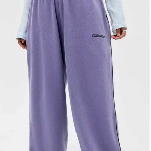 Lila Iets Frans - Mysiga lila mjukisbyxor från Iets Frans med bred passform och resår i midjan. Byxorna är gjorda i fleece och har en svart logga på ena benet. Perfekta för chill dagar eller när du vill vara extra bekväm. Använda en gång så praktiskt taget nyskick! 