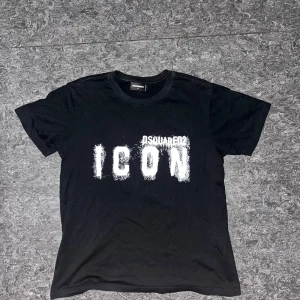 Svart Dsquared2 ICON t-shirt - Svart t-shirt från Dsquared2 i storlek M med stor vit 'ICON'-text framtill. Klassisk rund hals och korta ärmar. Tillverkad i mjuk bomull för en skön känsla. Snygg och stilren design med streetkänsla. Aldrig använd. 