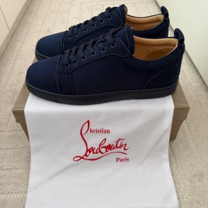 Mörkblå sneakers från Christian Louboutin - Snygga mörkblå sneakers från Christian Louboutin i mocka med klassisk röd sula och diskret broderad logga på hälen. Skorna har rund tå, snörning och en stilren design som passar perfekt till jeans eller dressade byxor. För flera bilder eller frågor så är de bara att slå ett pling sick 9,5/10 priset kan diskutera vid snabb affär.