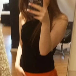 Svart korsad topp  - Säljer en korsad topp med stilren och enkel design. Toppen är ärmlös och har en asymmetrisk skärning över axeln, vilket ger en trendig look. Perfekt att matcha med både jeans och kjol för en snygg outfit.