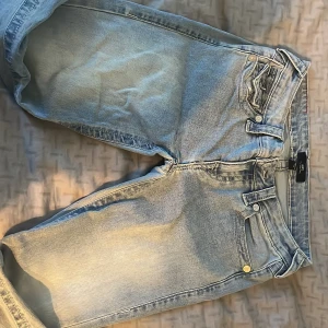 True Religion ljusblå bootcut jeans - Säljer ett par ljusblå jeans från True Religion med klassiska kontrastsömmar och stora bakfickor med lock och knappar. Jeansen har bootcut-modell och är tillverkade i denim med snygg tvätt. Märkespatch bak i midjan och detaljerade fickor ger en unik look. Pris går såklart att diskutera, jag säljer pågrund av att jag har så många par jeans. Jeansen passar dig som är 160 och uppåt. 