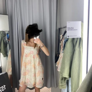 Blommig kortklänning med volang - Supersöt kortklänning med blommigt mönster i ljusa pastellfärger. Klänningen har volangdetaljer nertill, fyrkantig urringning och är ärmlös med breda axelband. 💗💗