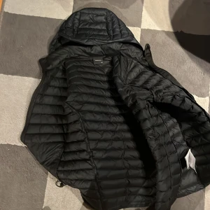 Svart jacka från Peak Performance - Säljer en stilren svart jacka från Peak Performance. Jackan har en huva och dragkedja framtill samt praktiska fickor med dragkedjor. Perfekt för en sportig look. Denna är perfekt för skidåkning och är varmare än majoriteten av jackor. Knappt använd och i toppen bra skick. Nypris 2000 kr