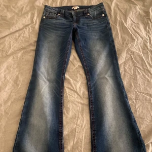 Blå bootcut jeans från Gina Tricot - Snygga blå jeans från Gina Tricot med bootcut-modell och röda sömmar. Jeansen har fina broderade bakfickor. De är lågmidjade och passar perfekt i längden på mig som är 170 cm. ❤️