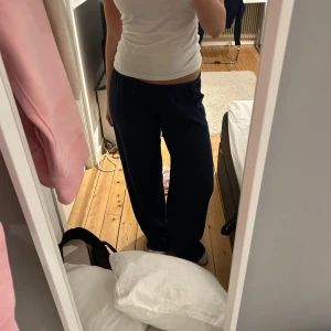 Mörkblå broderade byxor från Nelly  - Mörkblå byxor från Nelly i storlek XS med broderat hålmönster och elastisk midja. Byxorna har en loose passform och är tillverkade i mjukt tyg, perfekta för en chill och avslappnad look.