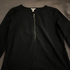 Svart långärmad tröja Calvin Klein - Svart långärmad tröja från Calvin Klein med rund halsringning och snygg silverfärgad dragkedja framtill. Tröjan har en stilren look. Perfekt för dig som gillar minimalistisk och clean stil.