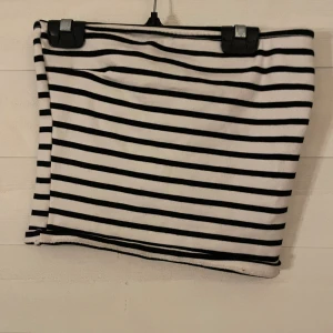 Randig tubtopp från Gina Tricot - Säljer en svartvit randig kortkjol från Gina Tricot. Kjolen har en tight passform och är gjord i mjukt bomullsmaterial. Perfekt för dig som gillar en enkel men stilren look med klassiska ränder.