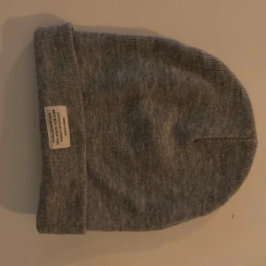 Grå ribbad mössa med etikett - Snygg grå mössa från Urban Classics med ribbad struktur och en vit etikett framtill. Perfekt för kyliga dagar och enkel att matcha med olika outfits. Klassisk design som funkar året runt.