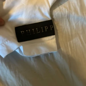 Vit Superman t-shirt Philipp Plein XL - Vit t-shirt från Philipp Plein i storlek XL med färgglatt Superman-tryck på framsidan och svart logga längs nederkanten. Klassisk rund hals och korta ärmar. Materialet känns som bomull och trycket är riktigt iögonfallande.