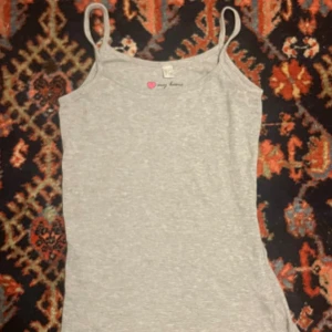 Grå linnetopp med tunna axelband - Säljer en enkel och grå linnetopp från My Love. Toppen har tunna axelband och är figurnära i modellen, perfekt att matcha med jeans eller kjol. Mjuk och skön bomullskänsla.