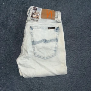 Nudie Jeans Tight Long  - Helt nya!Ljusblå skinny jeans från Nudie Jeans, modell Tight Long John i färgen Arctic Sea. Klassisk femficksdesign, smal passform och stretchigt jeanstyg. Snygga kontrastsömmar på bakfickorna och läderpatch med logga bak i midjan. Färgen kan även upplevas vit ! Midja 33cm, längd 104cm. Ifall det inte finns någon bild i annonsen där jag bär plaggen jag säljer så är det för att jag ej kan ha storleken heller passformen, så kolla måtten för storlek och googla på modellnamnet för passform 😉