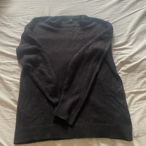 Svart stickad tröja från FSBN - En svart stickad tröja från FSBN i storlek S. Tröjan har rund halsringning, ribbade muddar vid ärmslut och nederkant samt långärmad passform. Tillverkad i 100% akryl och passar perfekt för kyligare dagar.
