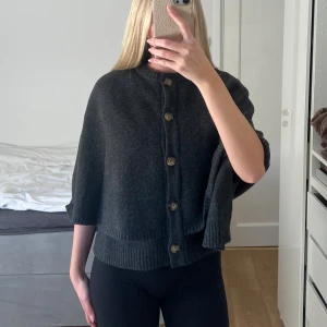 Mörkgrå kofta med knappar - Säljer en mörkgrå, loose-fit kofta med stora träknappar framtill. Koftan har en rak, boxig passform och är stickad i ett mjukt material. Perfekt för lager-på-lager och chill höst- eller vinterstil. 