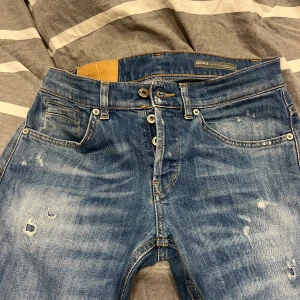Feta dondup jeans med slitningar - Säljer ett par blå jeans från märket dondup med snygga slitningar och tvättade detaljer. Klassisk femficksmodell med raka ben och knappgylf. Jeansen är nästan inte används endast ett fåtal gånger inga defekter:)