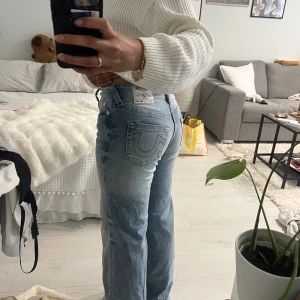 True Religion Bobbi baggy jeans ljusblå - Säljer ett par ljusblå True Religion Bobbi Low Slung Baggy jeans med röd kontrastsöm och klassiska bakfickor med broderad logga. Jeansen har låg midja och en loose, baggy passform. Tillverkade i mjukt denimtyg för en avslappnad vibe. I sista bilden ser man att vi sydd upp den lite för att det var för lång för mig! Är 160cm lång☺️ kan ta bort ifall man vill.  Har haft den ungefär 2-3 gånger bara.