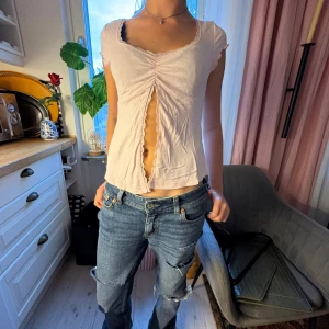 Ljusrosa croppad topp med snörning - Säljer en ljusrosa💗 croppad topp med korta ärmar och snygg snörning framtill som skapar en öppen detalj. Toppen har v-ringning med spetskant och är tillverkad i mjuk bomull. 🥰Perfekt för dig som gillar trendiga och feminina plagg. Toppen är från Gina tricot 💖