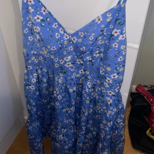 Blommig blå klänning med smock baktill - Supersöt blå klänning med vita och gula blommor 🌼Tunna axelband, smock i ryggen och lätt, luftigt tyg 