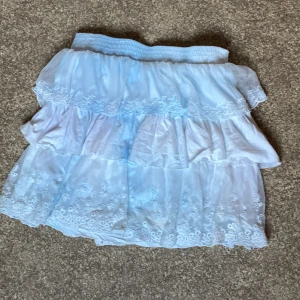 Ljusblå volangkjol från KappAhl - Supersöt ljusblå kortkjol från Vintage Stories by KappAhl med flera lager volanger och broderade spetsdetaljer. Den är lite urblekt, men har inga andra defekter.