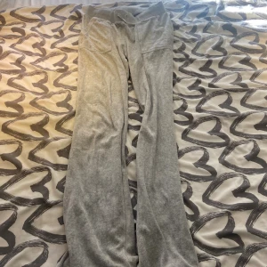 Grå mjukisbyxor med fickor - Grå mjukisbyxor i mjukt material med bred resår i midjan och två fickor med lock och knappar bak. Perfekta för chill dagar och har en avslappnad passform. Snyggt basic-plagg som funkar året runt.